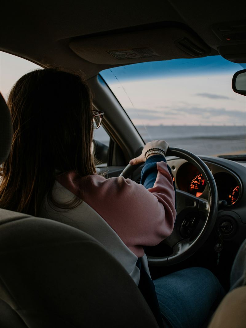 Motorista habilitada ao volante, com as duas mãos na direção.